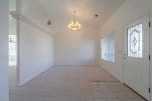 Foyer with light carpet, ceiling fan with notable chandelier, and lofted ceiling