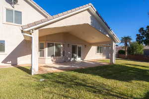 Back of property with a lawn and a patio area