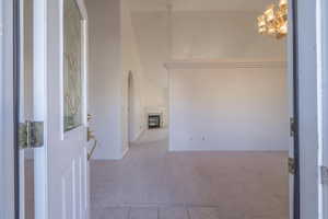 Entryway with light colored carpet, a high ceiling, and a notable chandelier