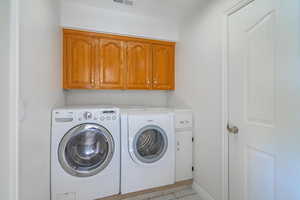 Laundry area featuring cabinets, light tile patterned flooring, and washer and dryer