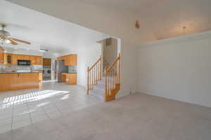 Unfurnished living room with ceiling fan, sink, light colored carpet, lofted ceiling, and washer / dryer