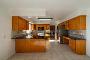 Kitchen with white range oven, independent washer and dryer, and tasteful backsplash