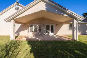 Back of house with a yard and a patio