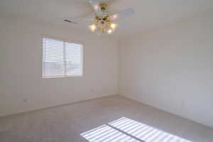 Carpeted spare room featuring ceiling fan