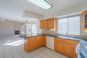 Kitchen featuring dishwasher, sink, kitchen peninsula, light tile patterned floors, and range