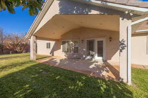 Back of property featuring a lawn, french doors, and a patio