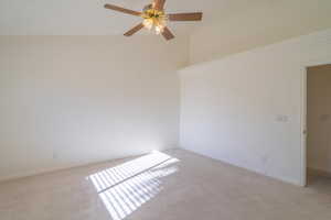 Unfurnished room featuring ceiling fan, lofted ceiling, and light carpet