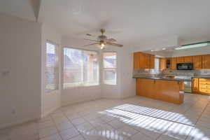 Kitchen featuring decorative backsplash, light tile patterned floors, white range with electric stovetop, kitchen peninsula, and a breakfast bar area