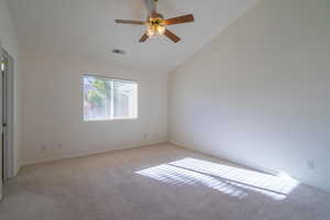 Empty room featuring light colored carpet and high vaulted ceiling