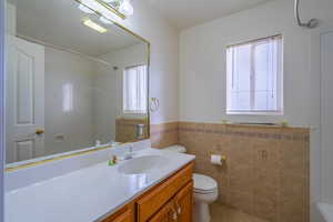 Bathroom featuring plenty of natural light, toilet, tile walls, and vanity