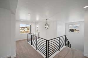 Corridor with a chandelier, a textured ceiling, and carpet floors