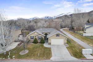 Ranch-style home featuring a mountain view, a front yard, and a garage