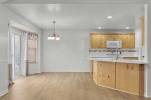 Kitchen featuring backsplash, a wealth of natural light, white appliances, pendant lighting, and an inviting chandelier