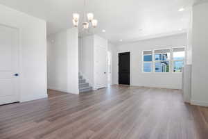 Empty room with a notable chandelier and wood-type flooring