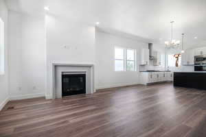 Unfurnished living room featuring a chandelier and dark wood-type flooring