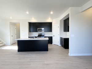 Kitchen with stainless steel appliances, quartz counters and black shaker cabinets.