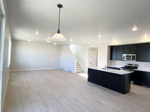 Great Room featuring a center island with sink, open floor plan, stainless steel appliances, and quartz countertops