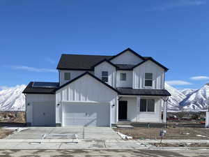 Modern farmhouse featuring a garage, metal roof, a standing seam roof, a mountain view, and board and batten siding