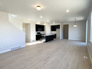 Great Room featuring a center island with sink, open floor plan, stainless steel appliances, and quartz countertops