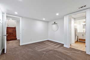 Unfurnished bedroom featuring ensuite bathroom and light carpet