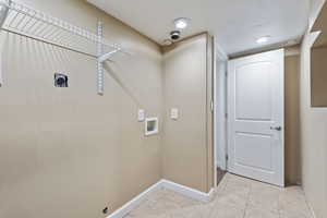 Clothes washing area with hookup for a washing machine, light tile patterned floors, and electric dryer hookup