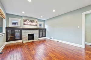 Unfurnished living room featuring a fireplace, hardwood / wood-style floors, and a wealth of natural light