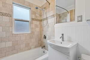 Full bathroom with vanity, tiled shower / bath combo, toilet, and a healthy amount of sunlight