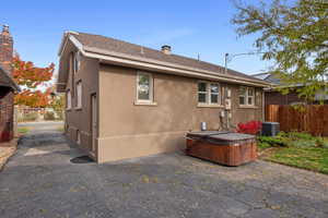 Rear view of property with central AC unit, a hot tub, and a patio