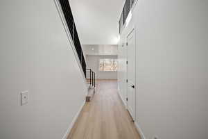 Hallway with a high ceiling and light wood-type flooring