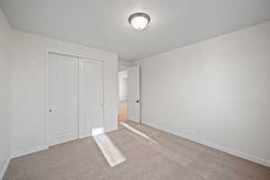 Unfurnished bedroom with light carpet and a closet