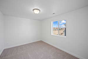 Carpeted empty room featuring a textured ceiling