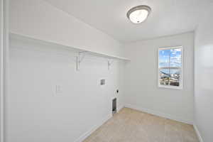 Washroom with electric dryer hookup, washer hookup, and a textured ceiling