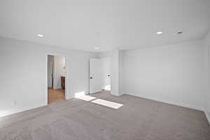 Unfurnished bedroom featuring ensuite bath and light colored carpet