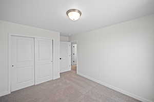 Unfurnished bedroom with light carpet and a closet