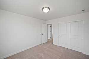 Unfurnished bedroom with light carpet, a closet, and a textured ceiling