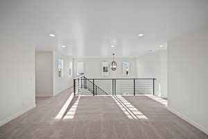 Spare room featuring light colored carpet and an inviting chandelier