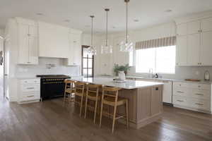 Kitchen featuring white cabinetry, a wealth of natural light, dishwasher, a center island, and range with gas stovetop