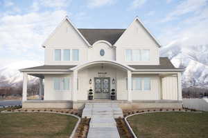 View of front of house featuring a mountain view, a front yard, french doors, and a porch