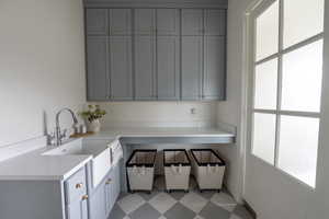 Laundry Room with sink, built in garbage, sink, cabinets to the ceiling, counter for folding laundry, timer lights