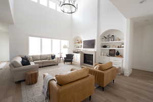 Living room with built in features, a towering ceiling, a notable chandelier, and LVP flooring