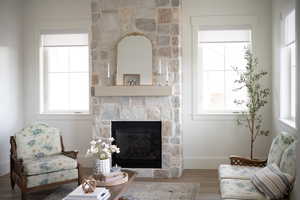 Living room with a wealth of natural light, a stone fireplace, and hardwood / wood-style floors