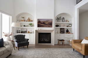 Living room featuring built in shelves, LVP flooring (paradigm), and a high ceiling