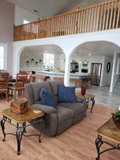 Living room with light hardwood / wood-style flooring and a towering ceiling