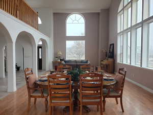 Dining room with light wood-type flooring and a high ceiling