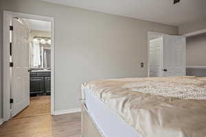 Bedroom featuring light wood-type flooring, ensuite bathroom, and a closet