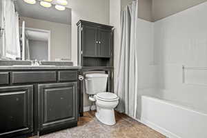 Full bathroom with tile patterned floors, vanity, toilet, and shower / tub combo with curtain