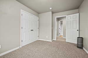 Unfurnished bedroom featuring light carpet and a closet