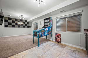 Rec room with a notable chandelier and light carpet