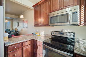 Kitchen with crown molding, light stone countertops, hanging light fixtures, and stainless steel appliances