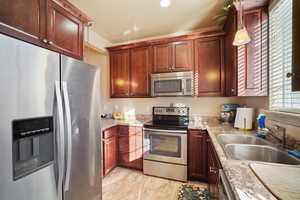 Kitchen with sink, hanging light fixtures, light tile patterned floors, a textured ceiling, and stainless steel appliances